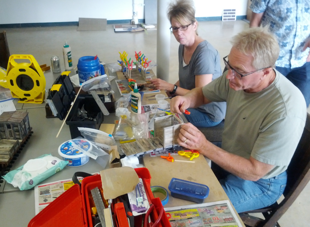 People sitting at a table building scale flatcars