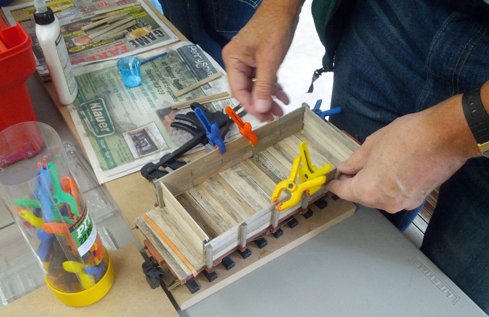 A club member clamps his flatcar project while the glue dries