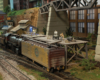 A small steam locomotive is coupled behind an ice-bunker reefer being loaded at an icing platform