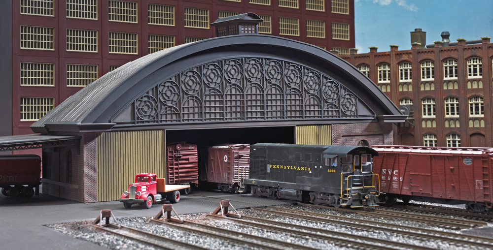 HO scale model of arched roof freight house with Pennsylvania Railroad switcher and boxcars