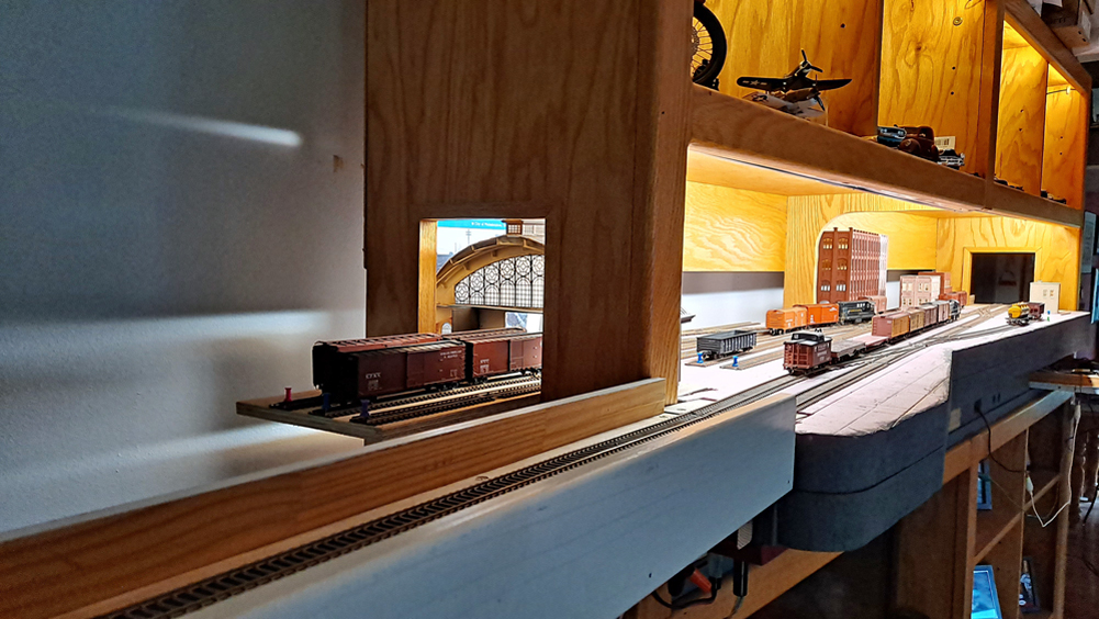 End view of layout with staging cassette in foreground, opening in end of entertainment center for freight house