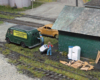 Model figures next to building and vehicles