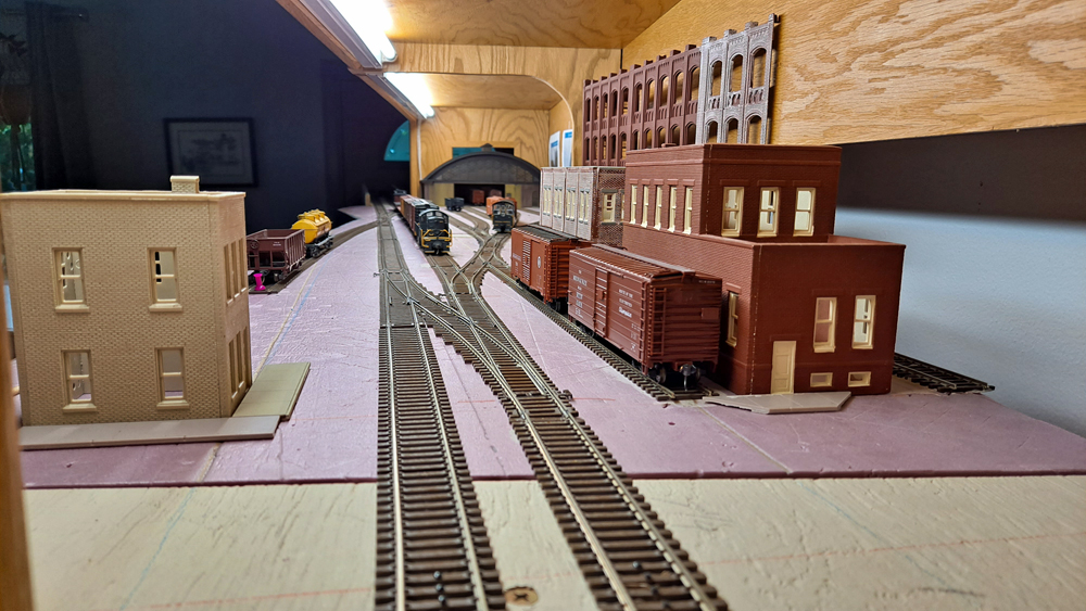 HO scale two track main line with siding on right in front of brick buildings