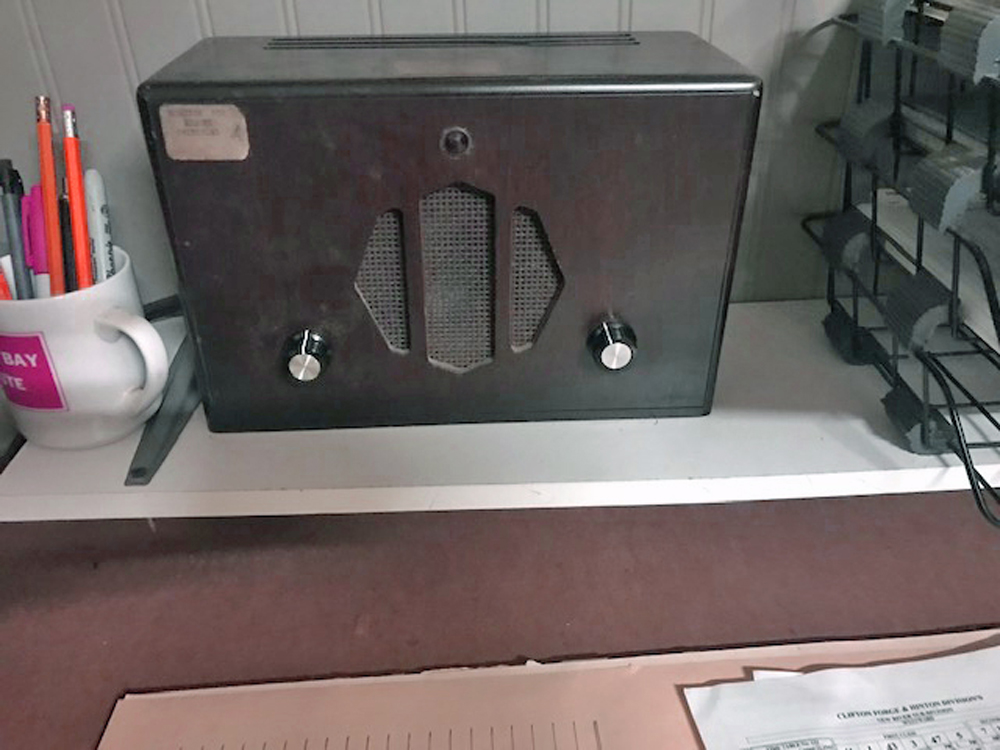 A vintage speaker sitting on a shelf next to a container of pencils