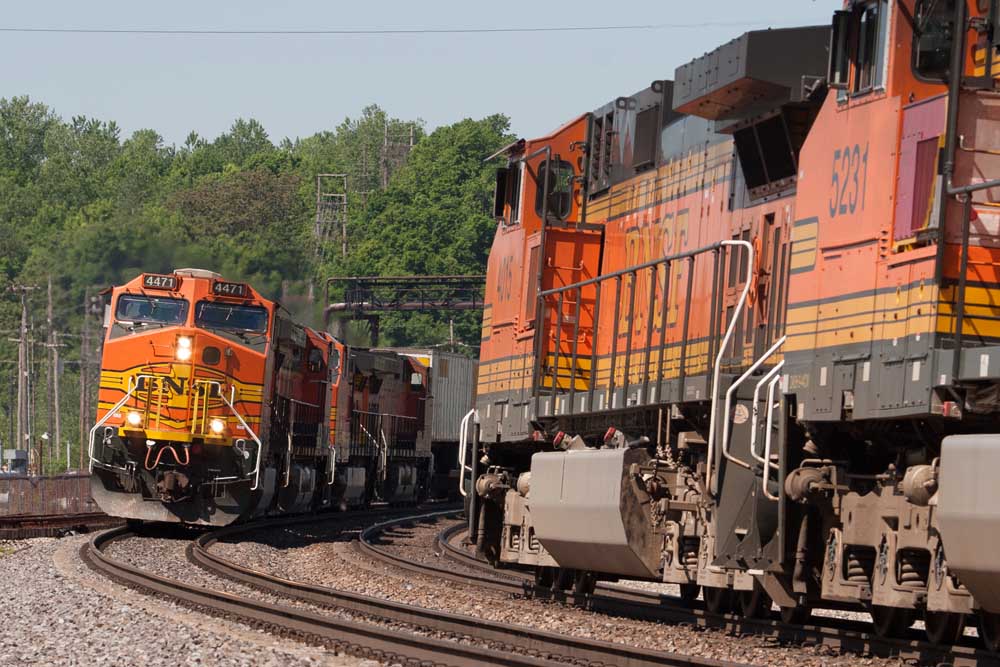 Freight trains with orange diesel locomotives pass on curve