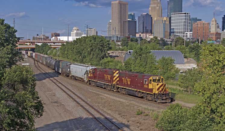 Maroon-and-red diesel locomotives with train and city skyline