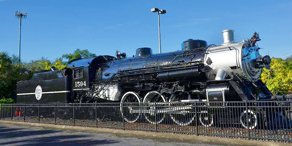Steam locomotive on display behind fence