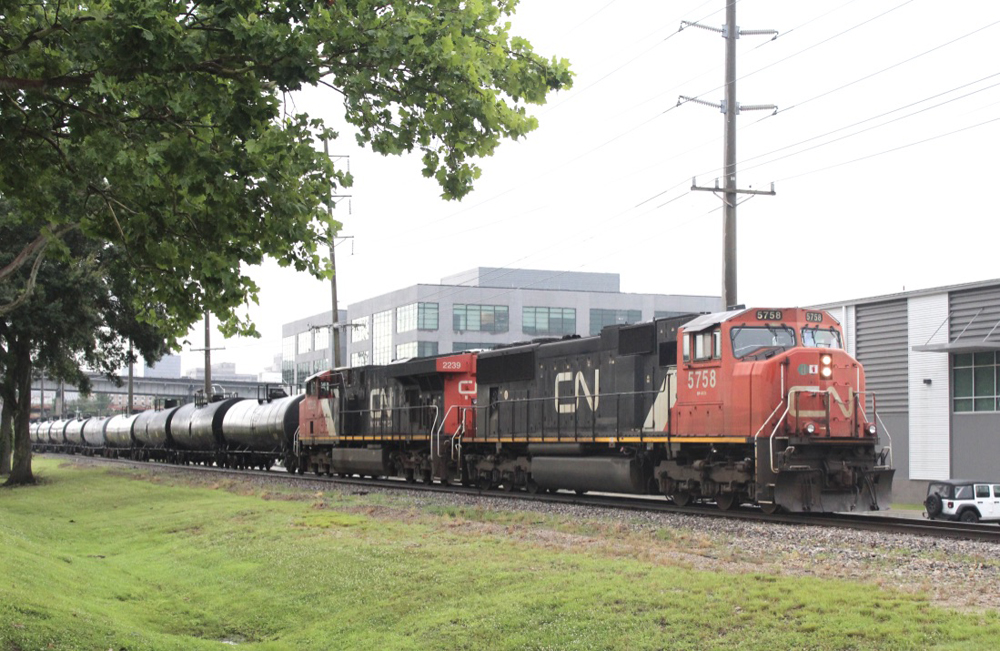 Black, white, and red locomotives pulling tank cars