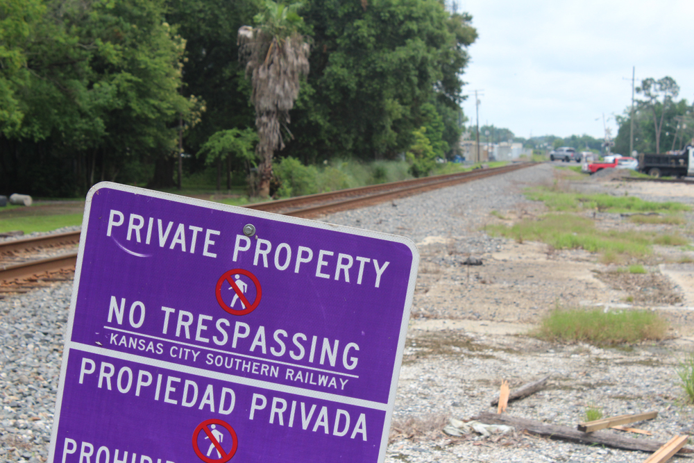 Vacant lot next to railroad tracks with Kansas City Southern no-trespassing sign in foreground.