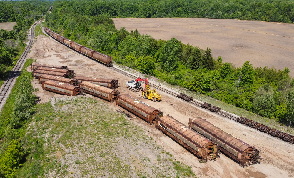 Cylindrical grain hopper cars off wheels, on ground