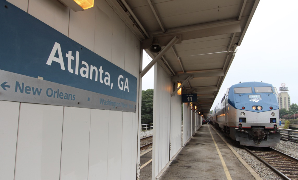 Passenger train at station with "Atlanta" sign in foreground