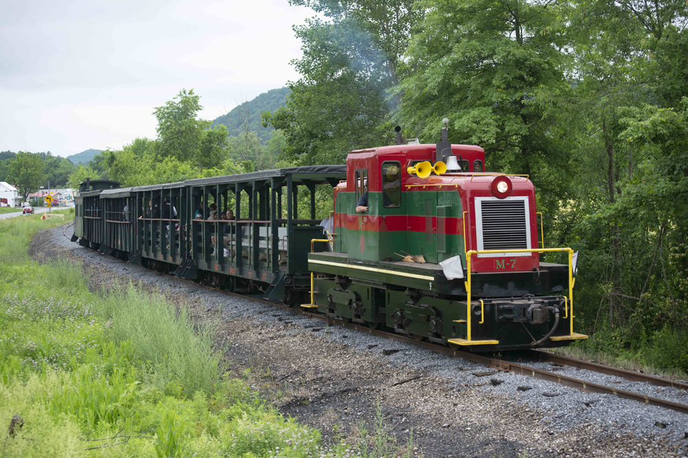 Red and green center-cab diesel hauls passenger train