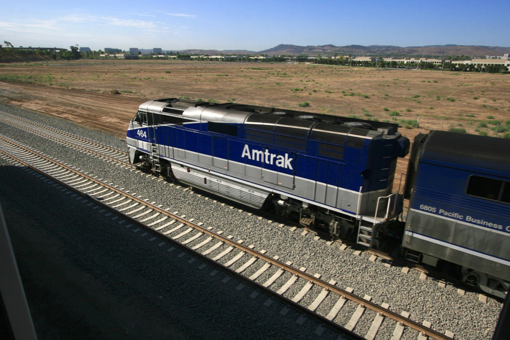 Blue and silver locomotive moves away from viewpoint above tracks