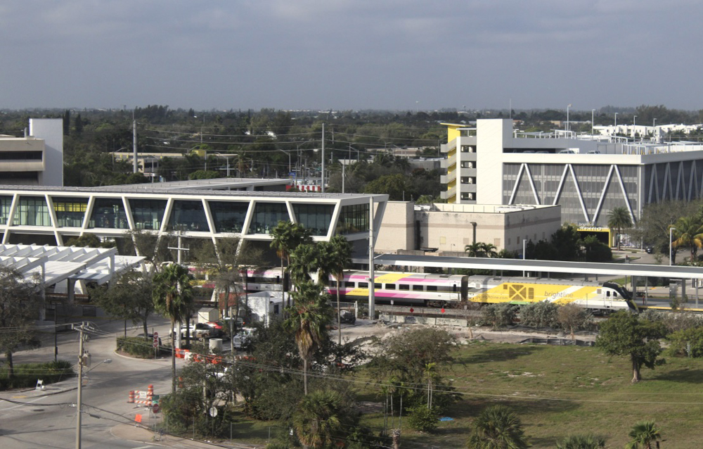 Passenger train and modern-design white station as viewed from across a field