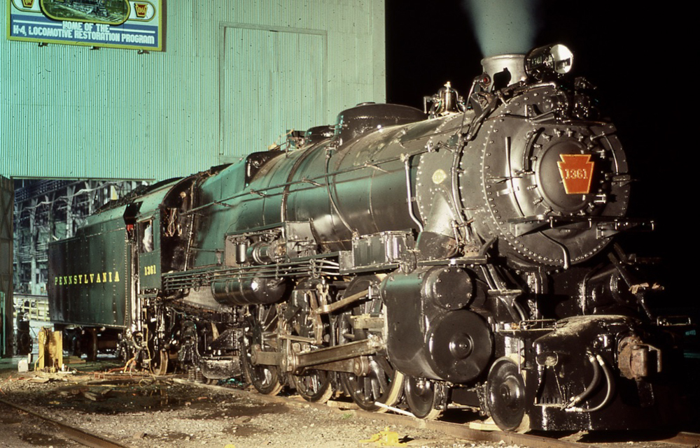 Steam locomotive outside shop building at night