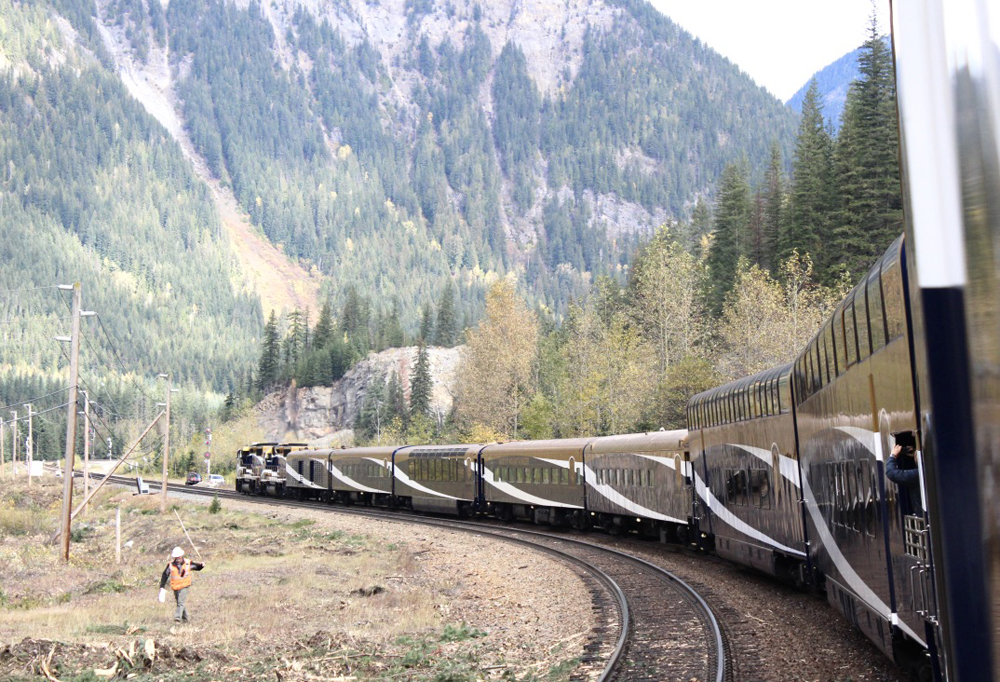 Passenger train rounds curve with Rocky Mountains in background