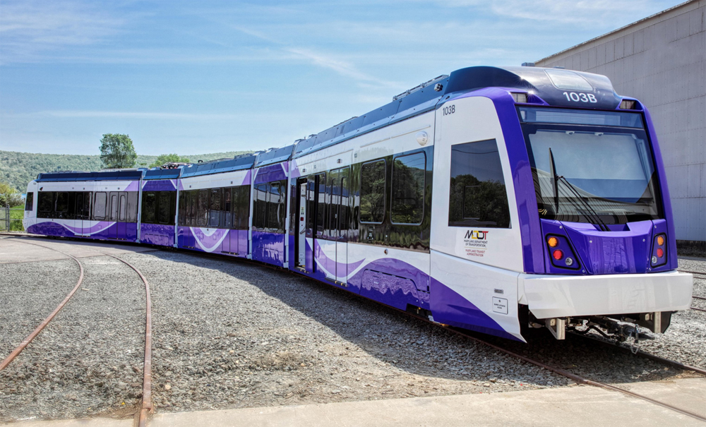 Purple and white light rail trainset parked on curve