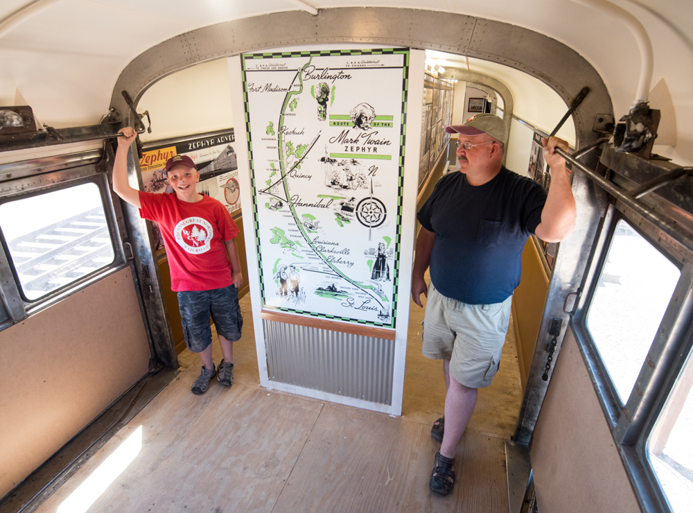 Two people in railroad car standing next to map