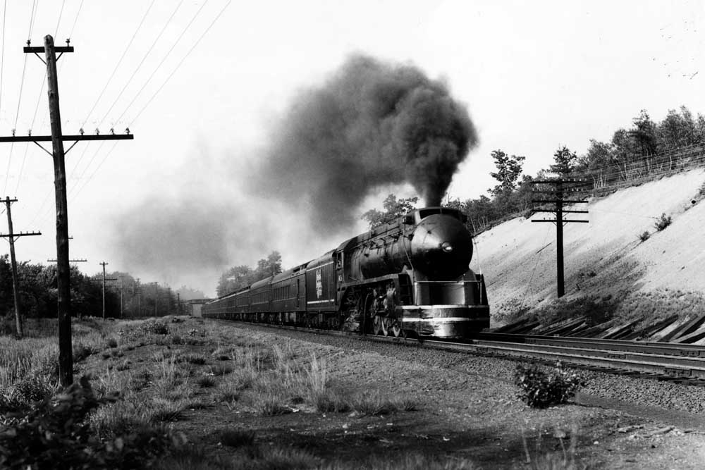 Streamlined steam locomotive with passenger train at speed