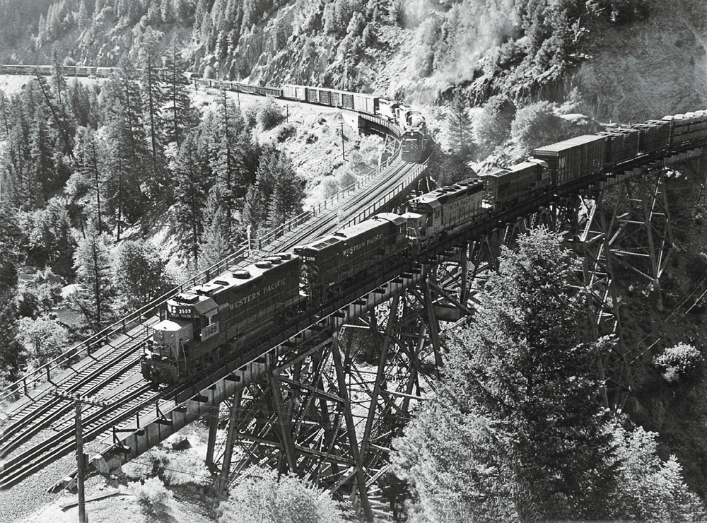 Road-switcher diesel locomotives with freight trains on trestles where two lines converge in mountains