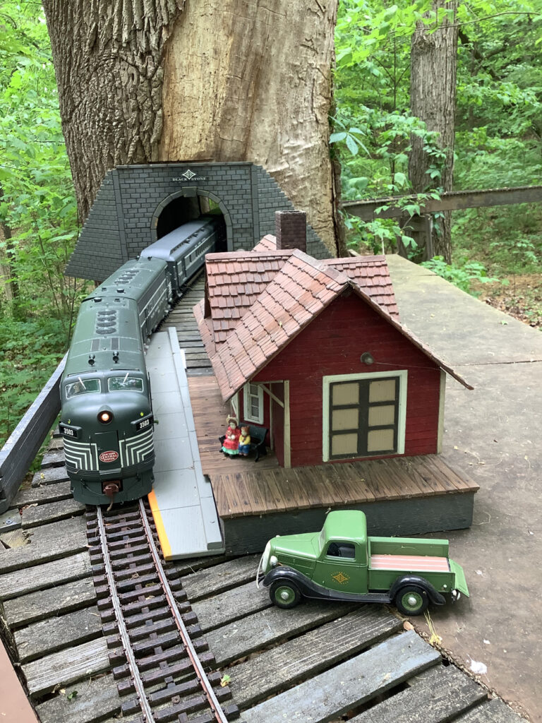 Tunnel through tree with locomotive on track and station