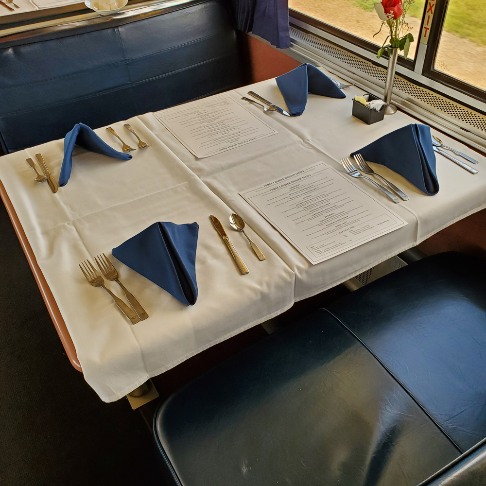 Table with white linen tablecloth and four place settings