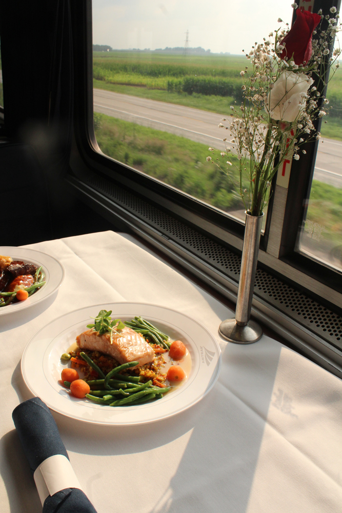 Plate of food on linen table cloth next to window of passenger car