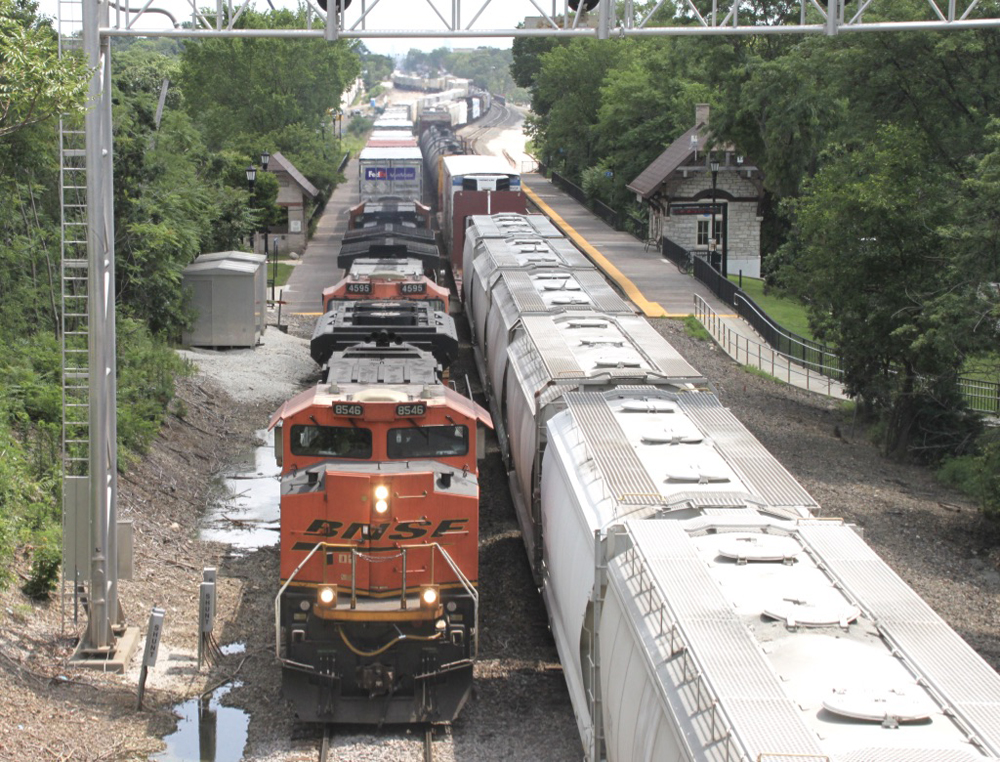 On three-track main, intermodal train on left-hand track catches up to freight train on center track.