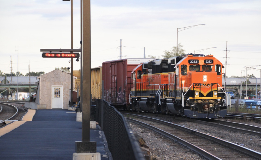 Freight train passing Metra station at BNSF Cicero Yard