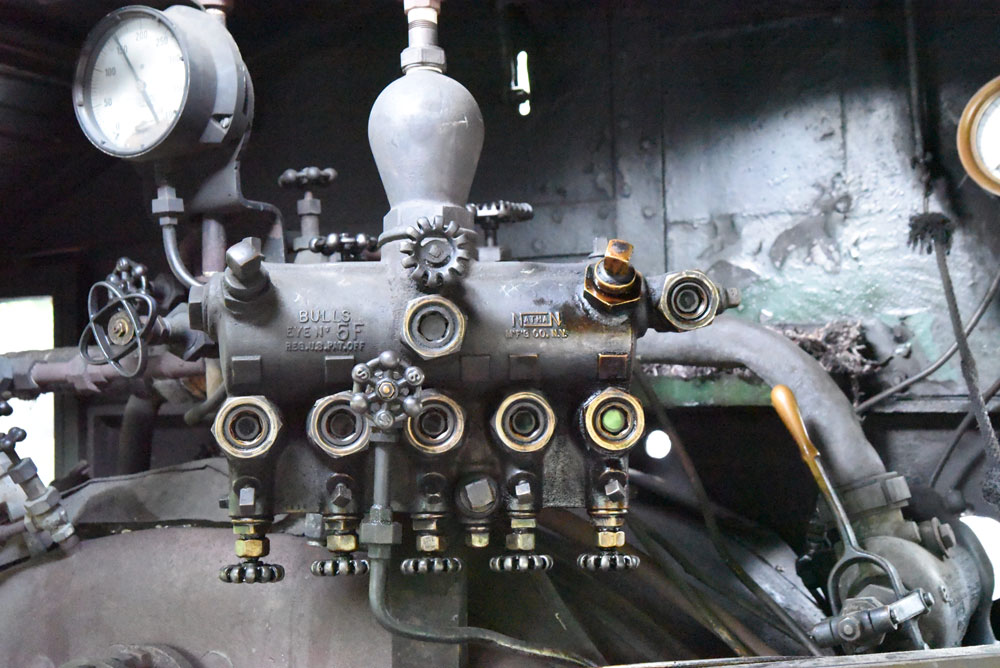 An array of knobs, piping, and other gear inside the cab of a steam locomotive.