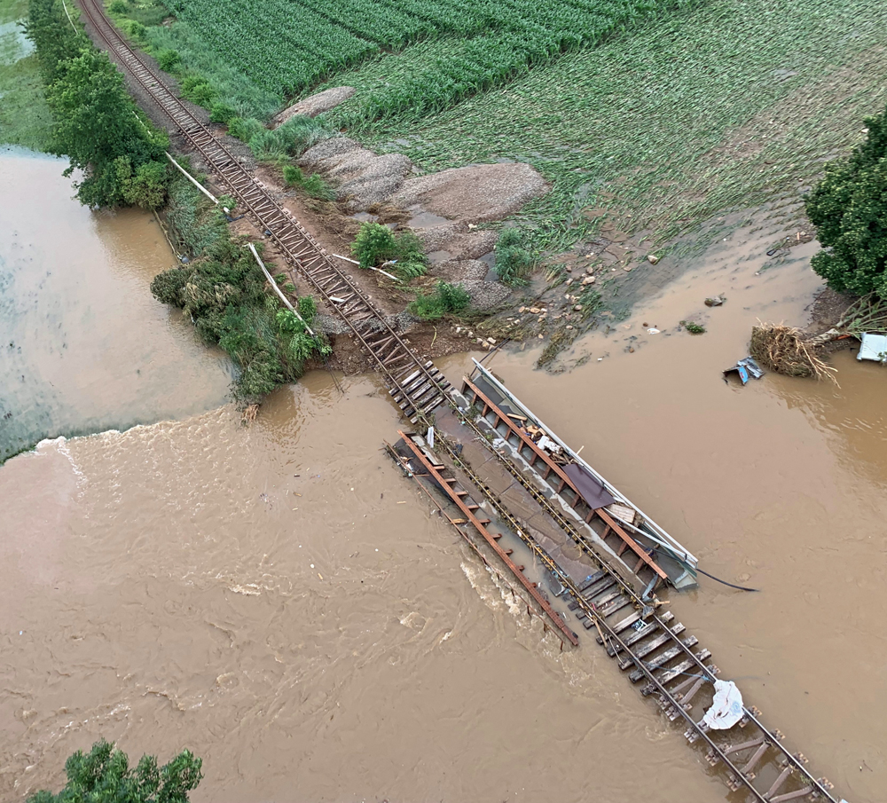 Washed-out bridge surrounded by muddy waters of swollen river