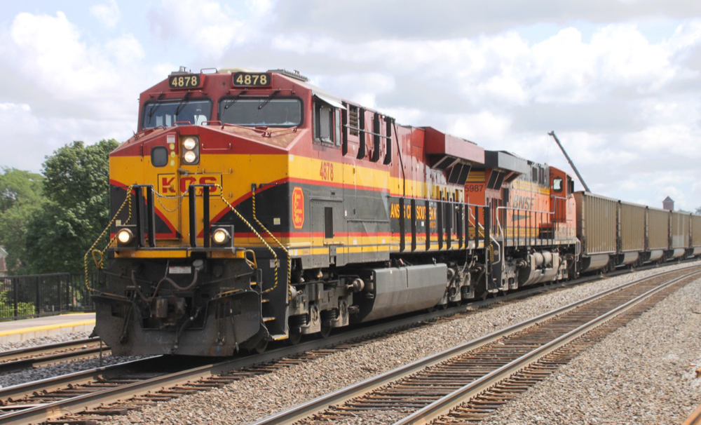 Red, black, and orange locomotive at head of freight train