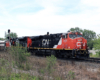 Two red and black locomotives with short passenger train passes signals