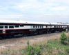 Black and white passenger cars with red trim — one with a glass back wall, one with a dome — pass on an inspection train.