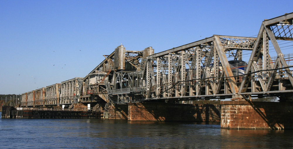 Long steel bridge with train barely visible through girders