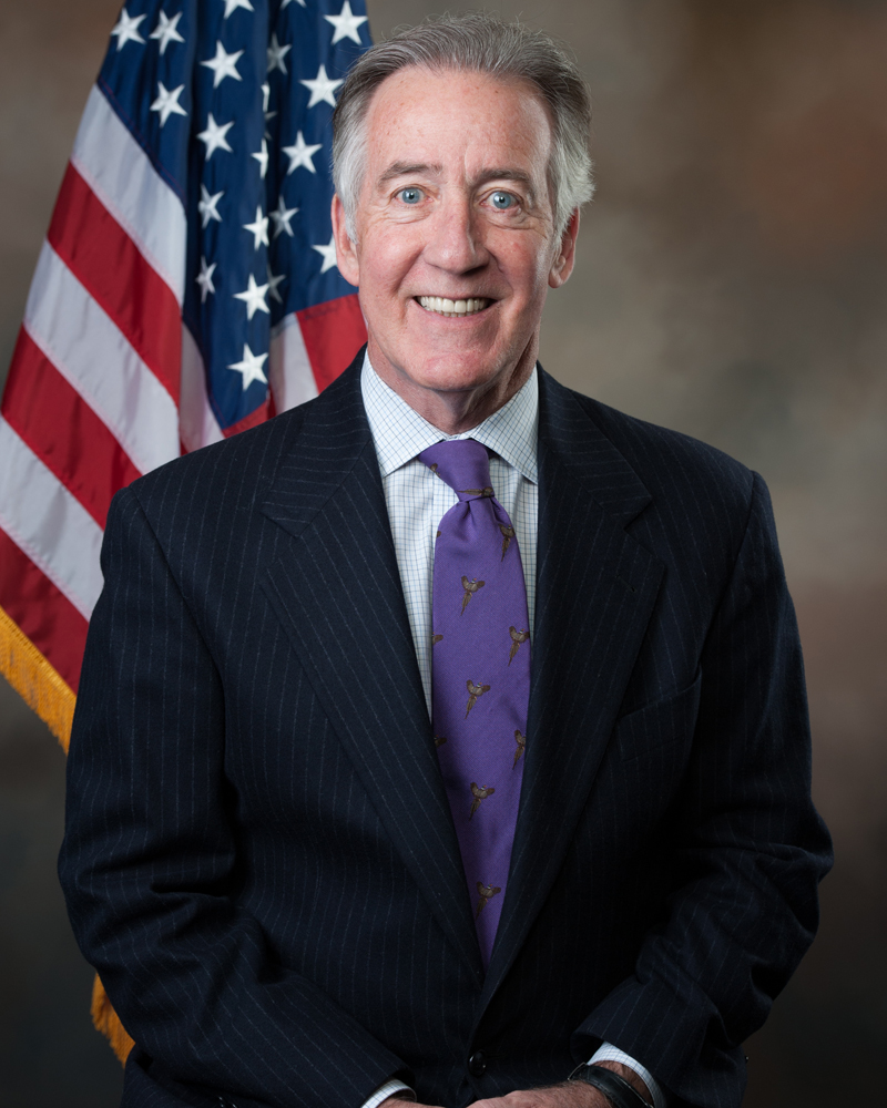 Congressman in dark suit in front of U.S. flag