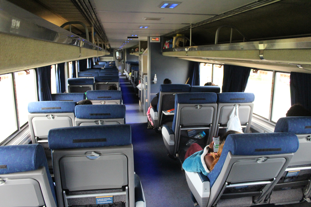 Interior of passenger car looking forward along aisle between coach seats
