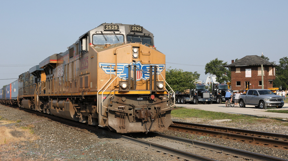 Train with yellow engines passes with tower in background