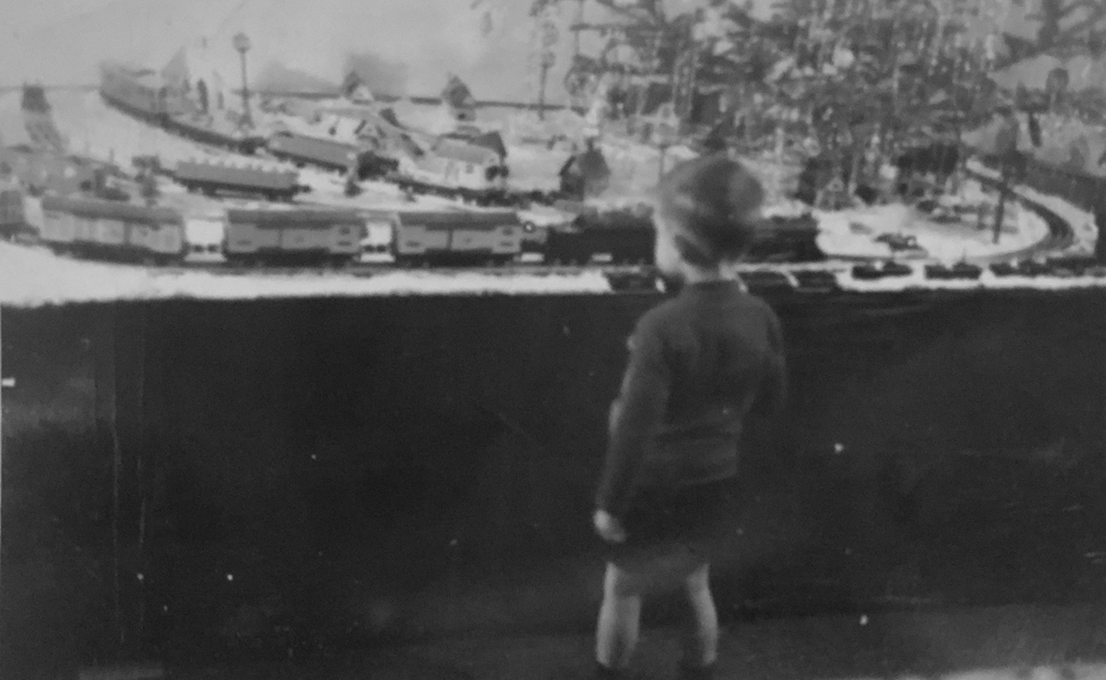 Vintage photo of small child watching toy trains run