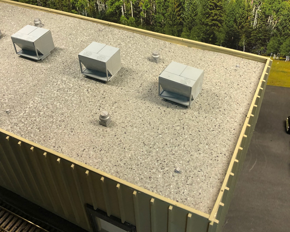  A model of a concrete building features a flat roof with a painted gravel texture.