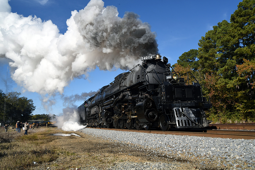 Steam locomotive smokes profusely among trees