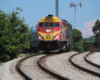 Red and yellow locomotive brings commuter train around sharp curve