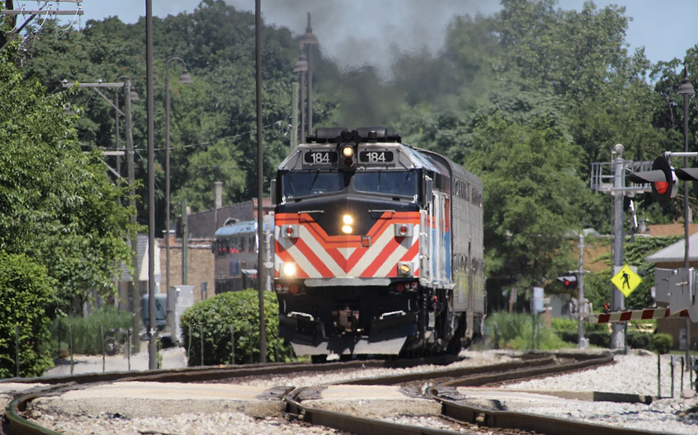 Train arrives at one-story brick station.