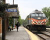 Train arrives at one-story brick station.