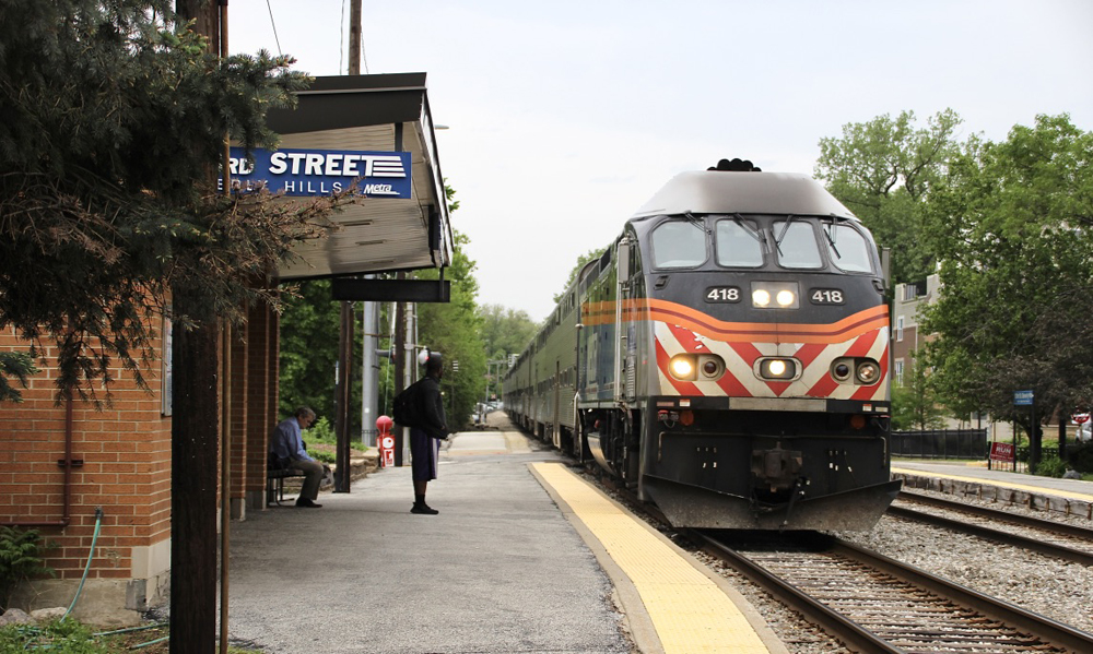 Train arrives at one-story brick station.