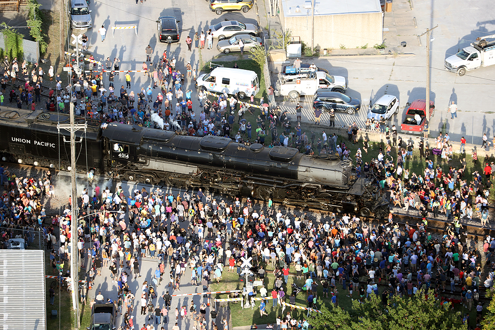 Paused Big Boy steam locomotive surrounded by large crowd of people.