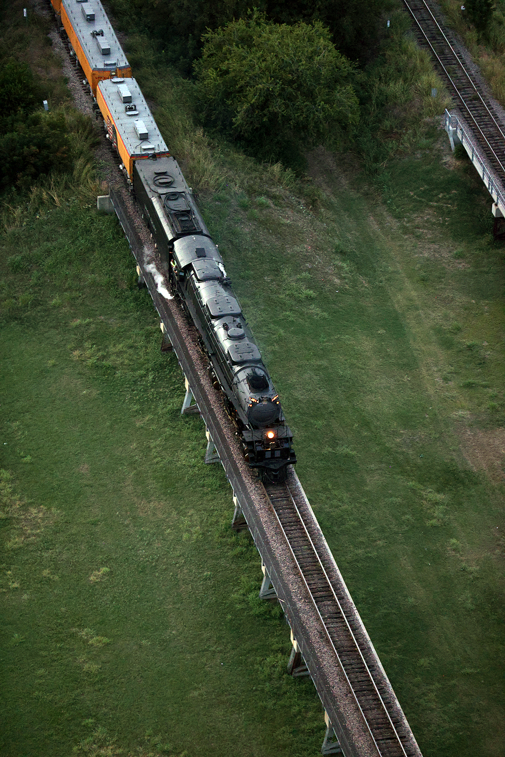 Big Boy steam locomotive in a low-light scene on an elevated viaduct.