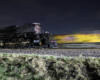 A yellow locomotive appears as a motion blur at night as the Big Boy steam locomotive is paused.