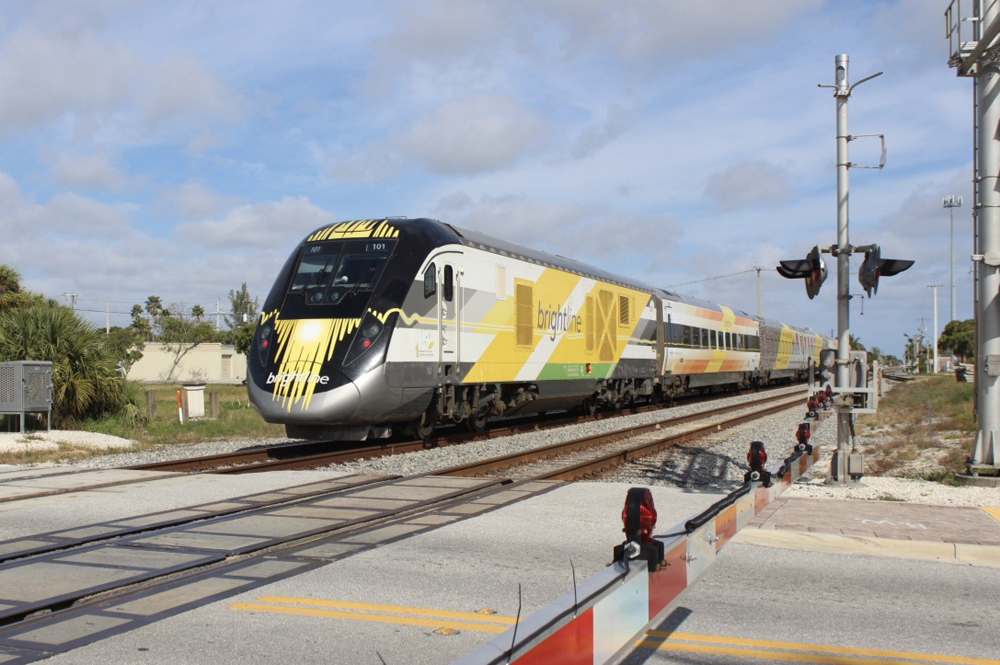 Yellow and white passenger train crosses street