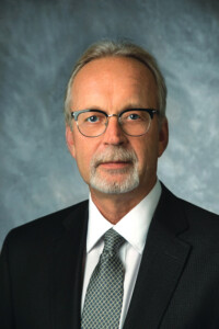 Head shot of man with glasses in dark suit coat